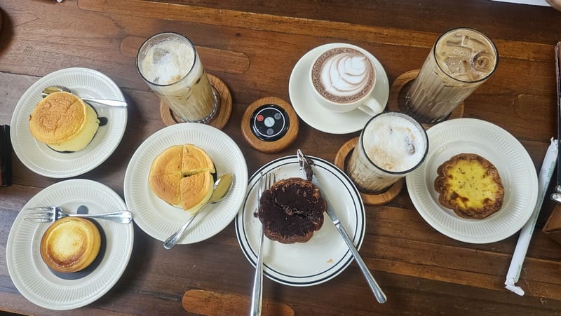 A table of pastries, egg tarts and iced coffees from above at 7AM Bakers and 7PM Diners
