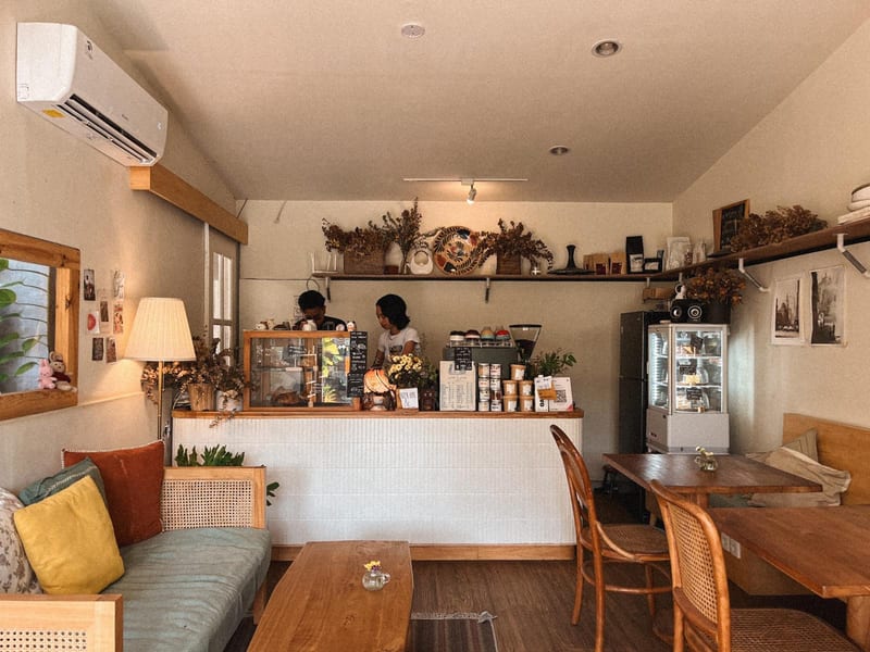 The interior with the serving counter, sofa and wooden tables at Decafo Cafe
