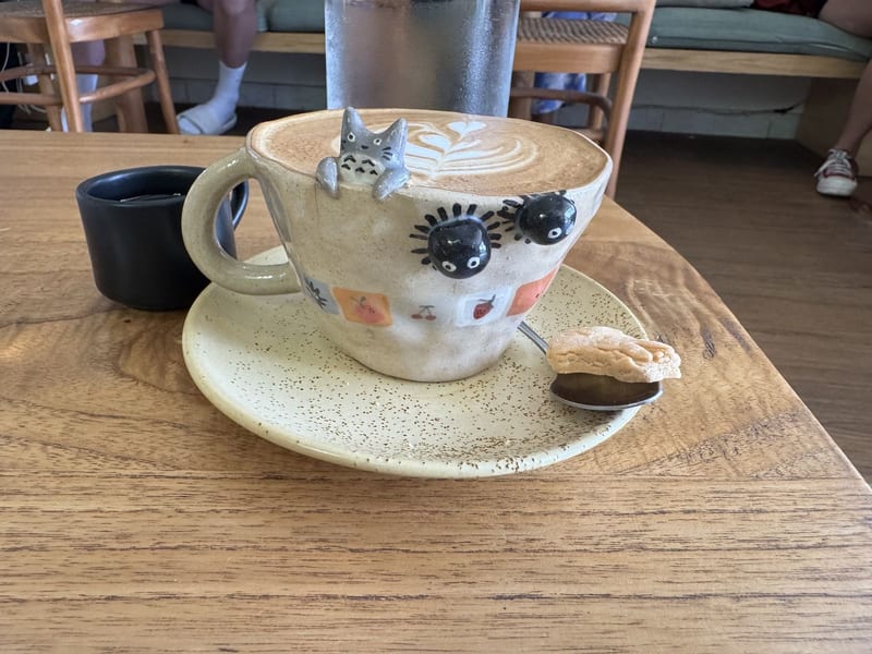 A latte in a hand-painted ceramic cup on a wooden table at Decafo Cafe