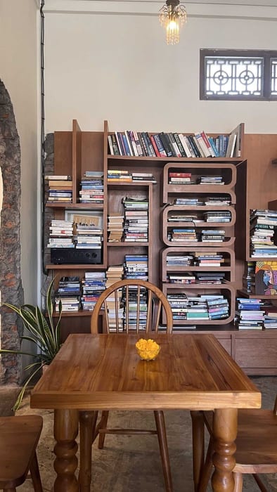 A wooden table in front of a wall of bookshelves at Littletalks Ubud