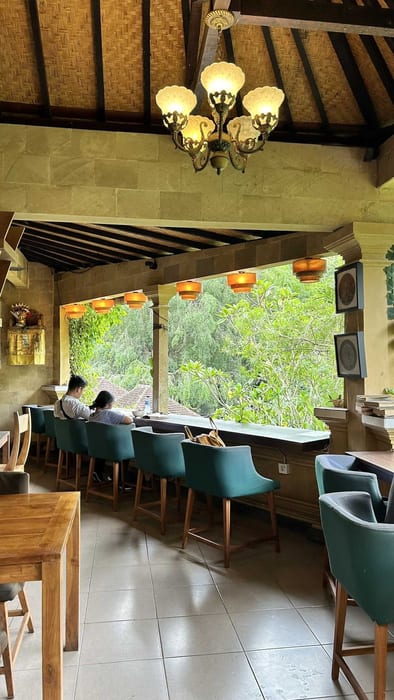 The terrace seating with teal chairs looking out to trees at Littletalks Ubud