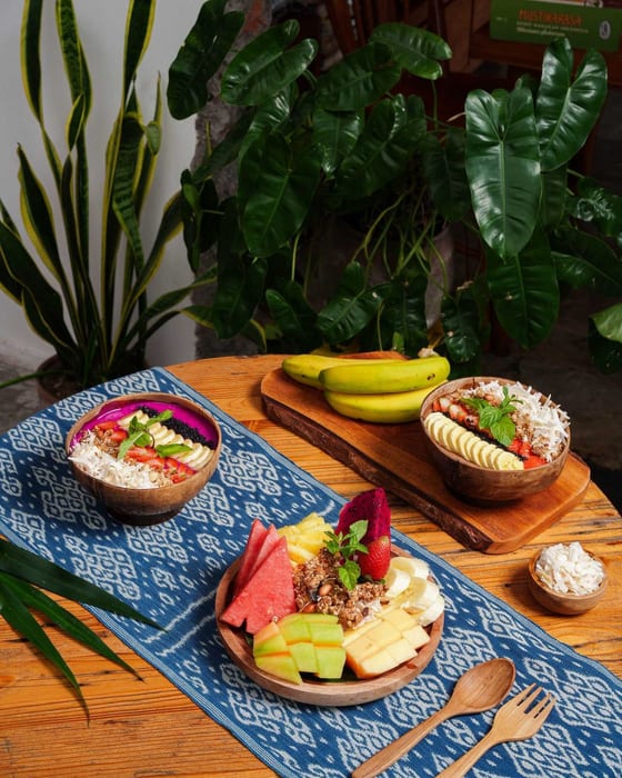 Smoothie bowls and a fruit platter on a batik runner at Littletalks Ubud