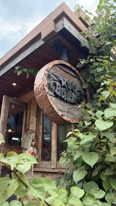 The round Roti Bohemia sign among bougainvillea at Roti Bohemia