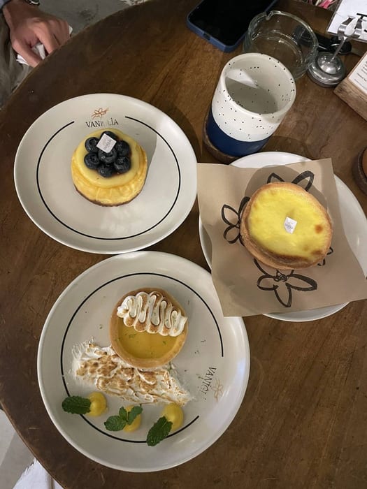 A blueberry tart, a lemon tart and a meringue slice on a round table at Vaniglia Gelato and Pastry
