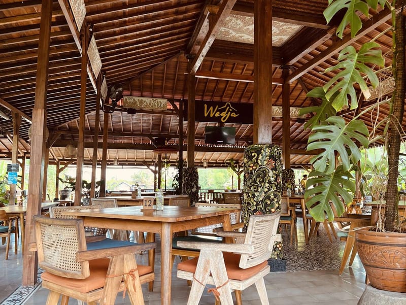 The timber pavilion interior with rattan chairs and monstera plants at Wedja Restaurant