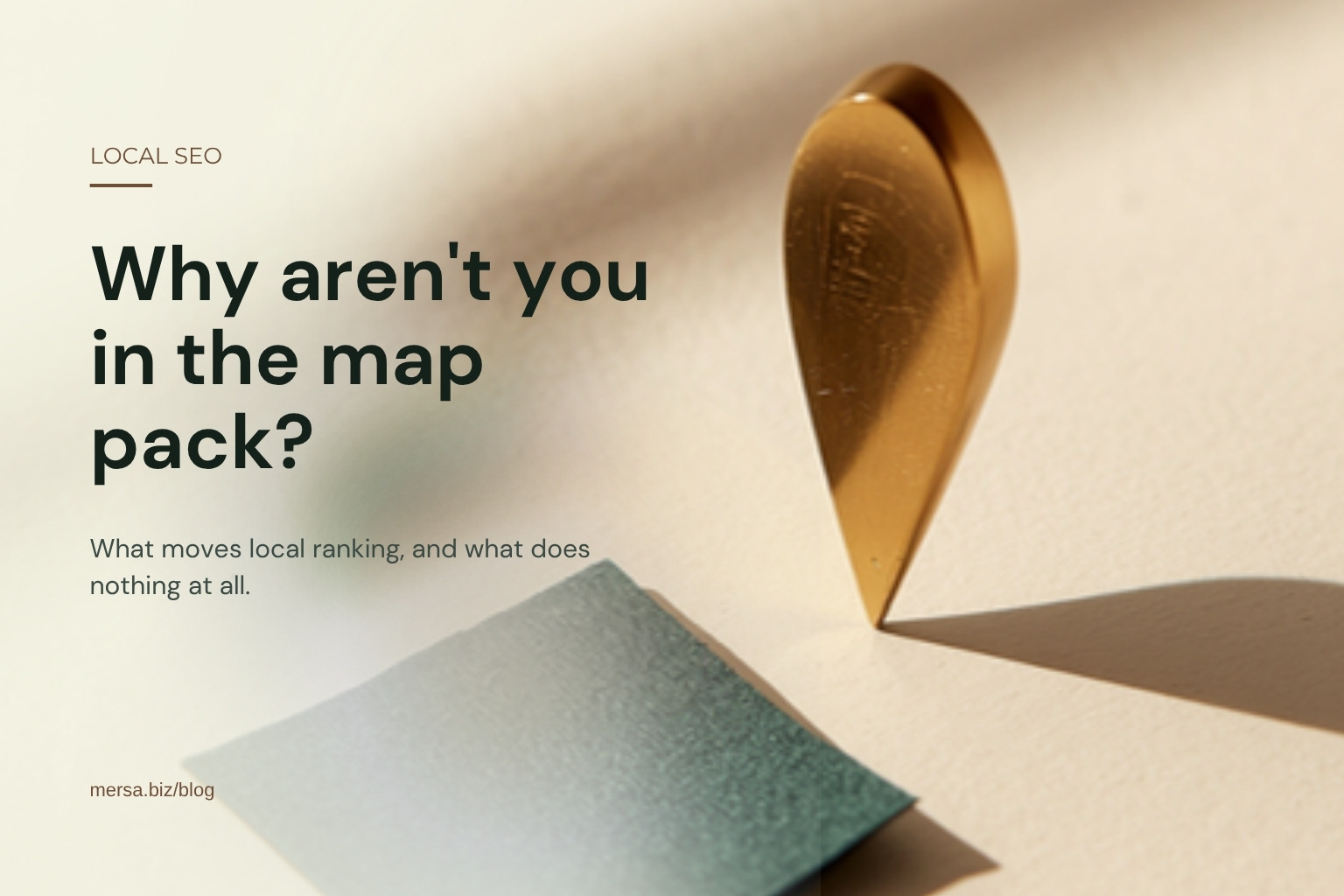 A brass teardrop map-pin marker standing on a cream surface beside a folded square of dark green cloth, captioned "Why aren't you in the map pack?".